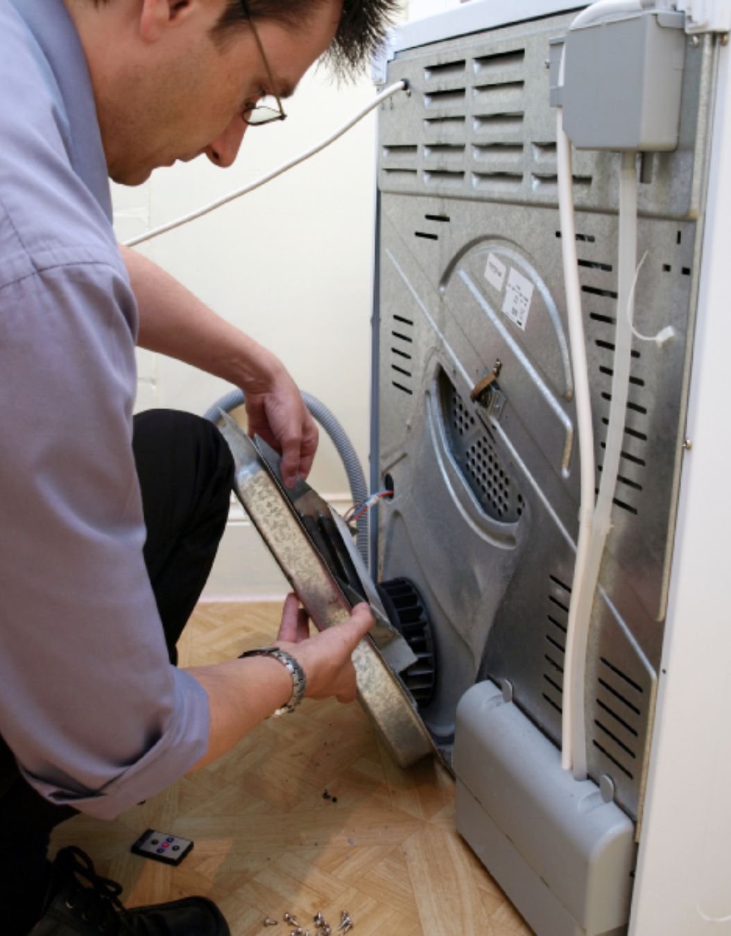 A man is engaged in fixing a washing machine, highlighting appliance repair services in San Francisco, CA.