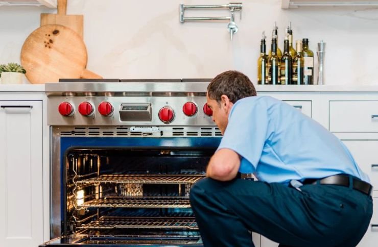 A man kneels to examine an oven, showcasing kitchen appliance repair services available in San Francisco, CA.