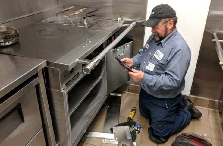 A technician works on a stove in a kitchen, highlighting commercial appliance repair services in San Francisco, CA.