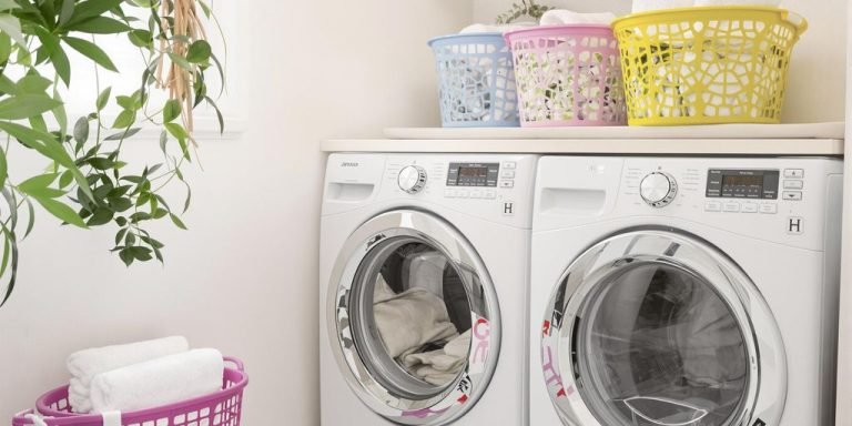 A tidy laundry room featuring a modern washer and dryer, with shelves and baskets for organization.