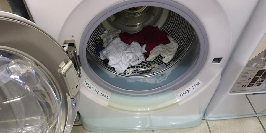  A washing machine filled with various clothes, showcasing a typical laundry scene in a domestic setting.