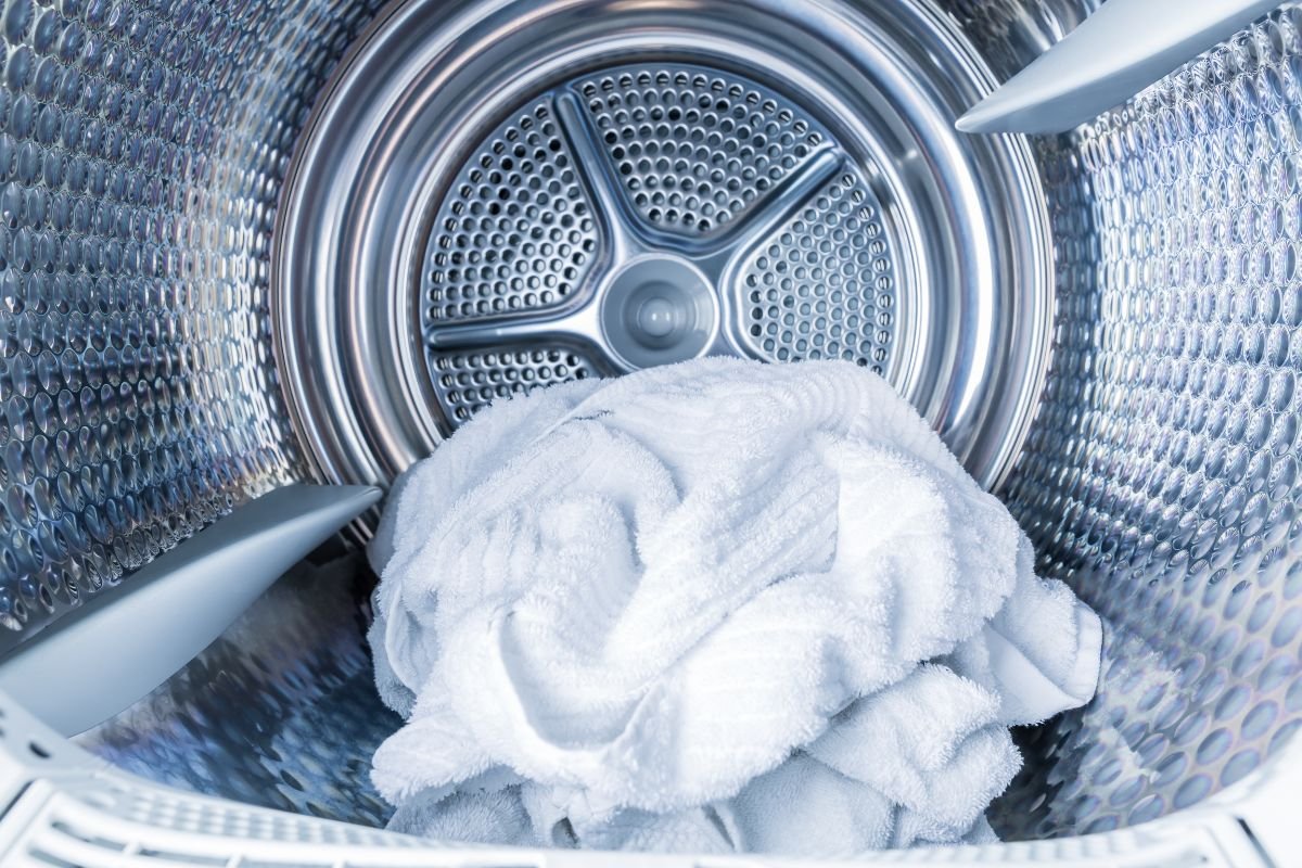 A clean white towel resting in the drum of a washing machine, awaiting laundry.